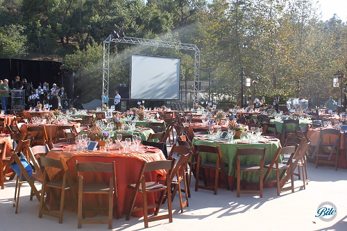 Tables and chairs set up in front of stage for outdoor fundraiser