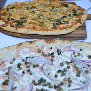Slicing assorted pizzas hot out of the oven at a pizza station