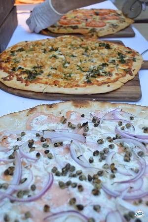 Slicing assorted pizzas hot out of the oven at a pizza station