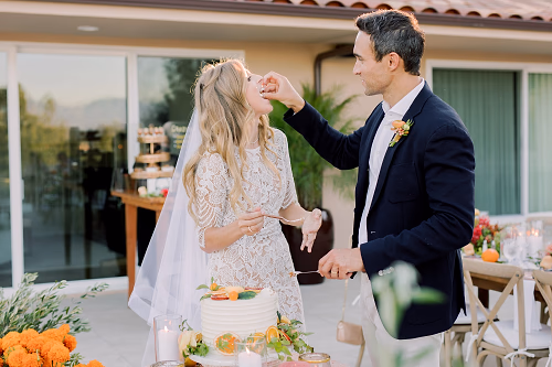 The groom feeds his beautiful bride and bite of their wedding cake