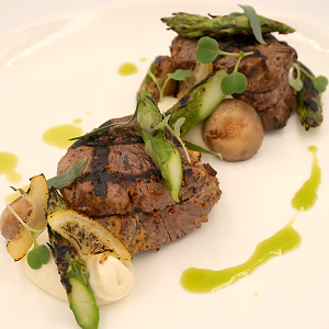 Beef medallions: grilled  wet aged with mustard and tarragon, flambéed mushrooms, pickled pearl onions, chive oil, and caramelized lemon. served with celeriac puree and charred asparagus  