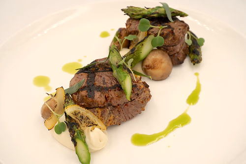 Beef medallions: grilled  wet aged with mustard and tarragon, flambéed mushrooms, pickled pearl onions, chive oil, and caramelized lemon. served with celeriac puree and charred asparagus  