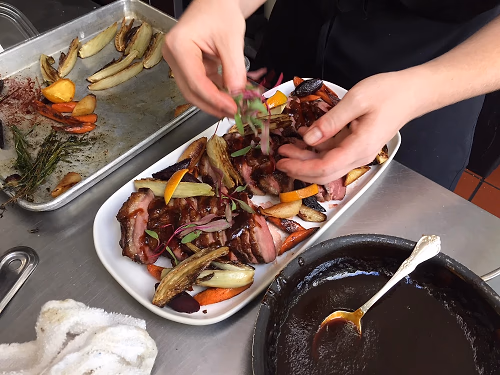 Chef plating a family-style duck platter