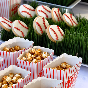 Caramel corn in individual popcorn boxes and baseball themed sugar cookies