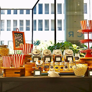 Popcorn bar with various popcorn flavors and toppings, with candy and snacks