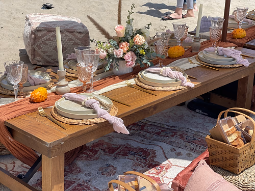 Table setting in the beach with fresh pink floral arrangements