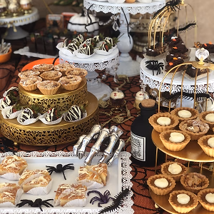 A Halloween dessert bar with mini autumn pies, mummy berries, dirt cups, ghost cupcakes, and gooey butter cake bars!