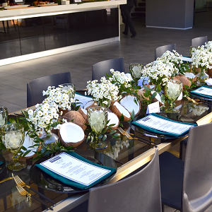 Table setting with elegant flower arrangements and coconut halves, each seat showcasing the menu