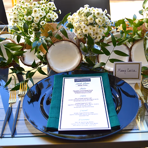 Close-up view of the table setting, featuring beautiful flower arrangements and coconut halves, each seat showcasing the menu