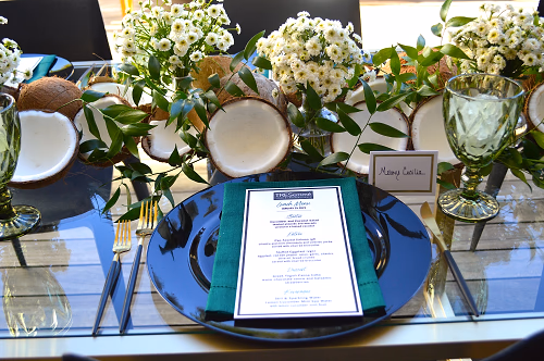 Close-up view of the table setting, featuring beautiful flower arrangements and coconut halves, each seat showcasing the menu