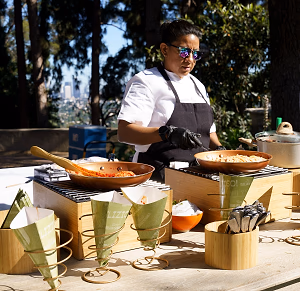 Chef in the action station for Tezza's pasta in a cone 